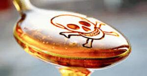 A spoonful of high fructose corn syrup with a skull and crossbones super imposed on the oil.